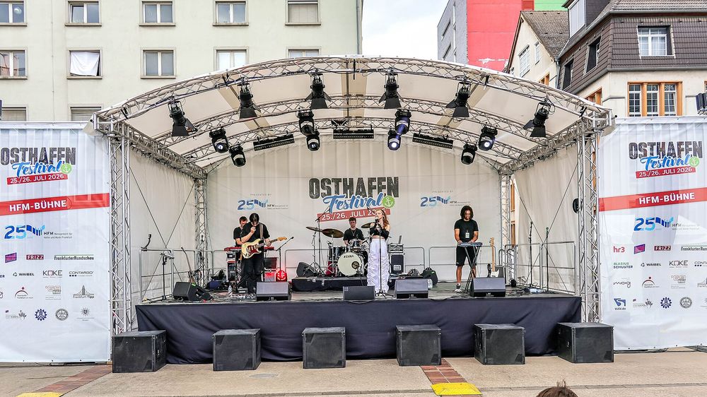 Large outdoor festival stage with lighting towers and an open crowd field