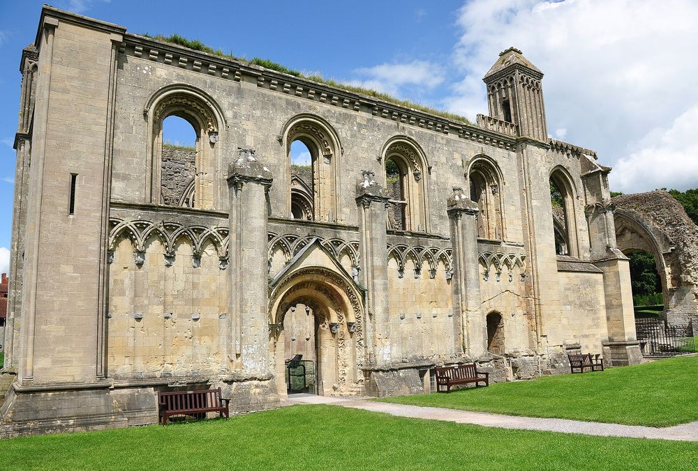 Ruins of Glastonbury Abbey set against green grass under an overcast sky.