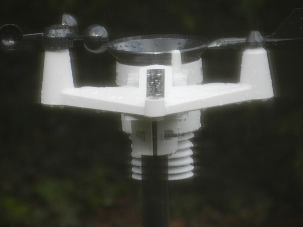 An anemometer weather instrument on a metal tower against a cloudy winter sky