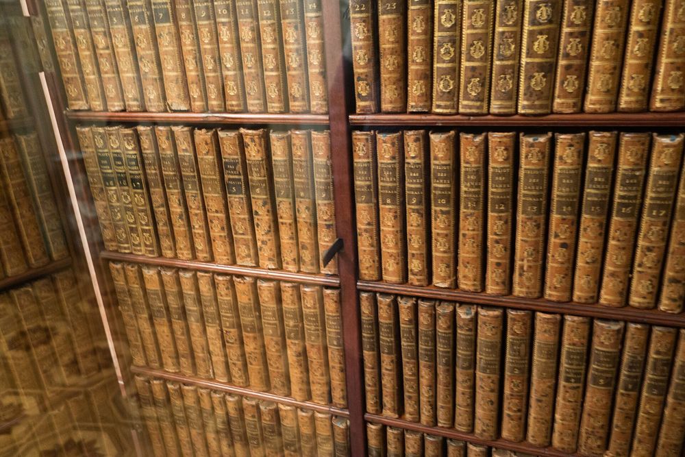 Vintage leather-bound books open on an oak library table beside an antique cartographic globe
