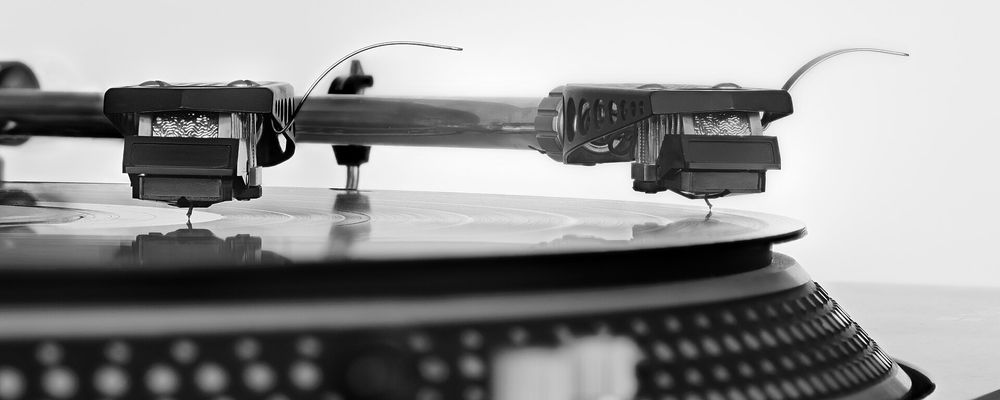 A close-up view of a vinyl record spinning on a turntable with the tonearm resting on the groove